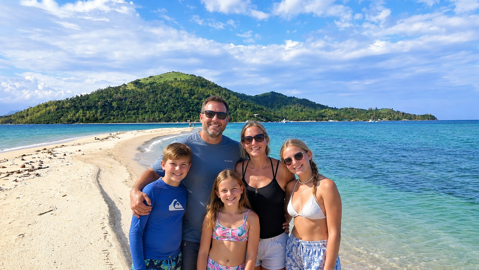 A family of five on a white sandbar with a green island behind them